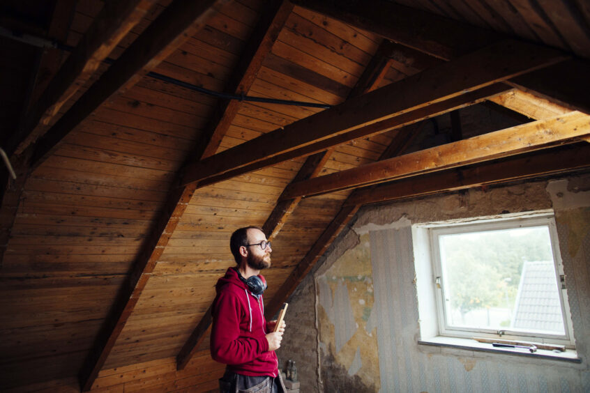 Side view of man inspecting attic under renovation